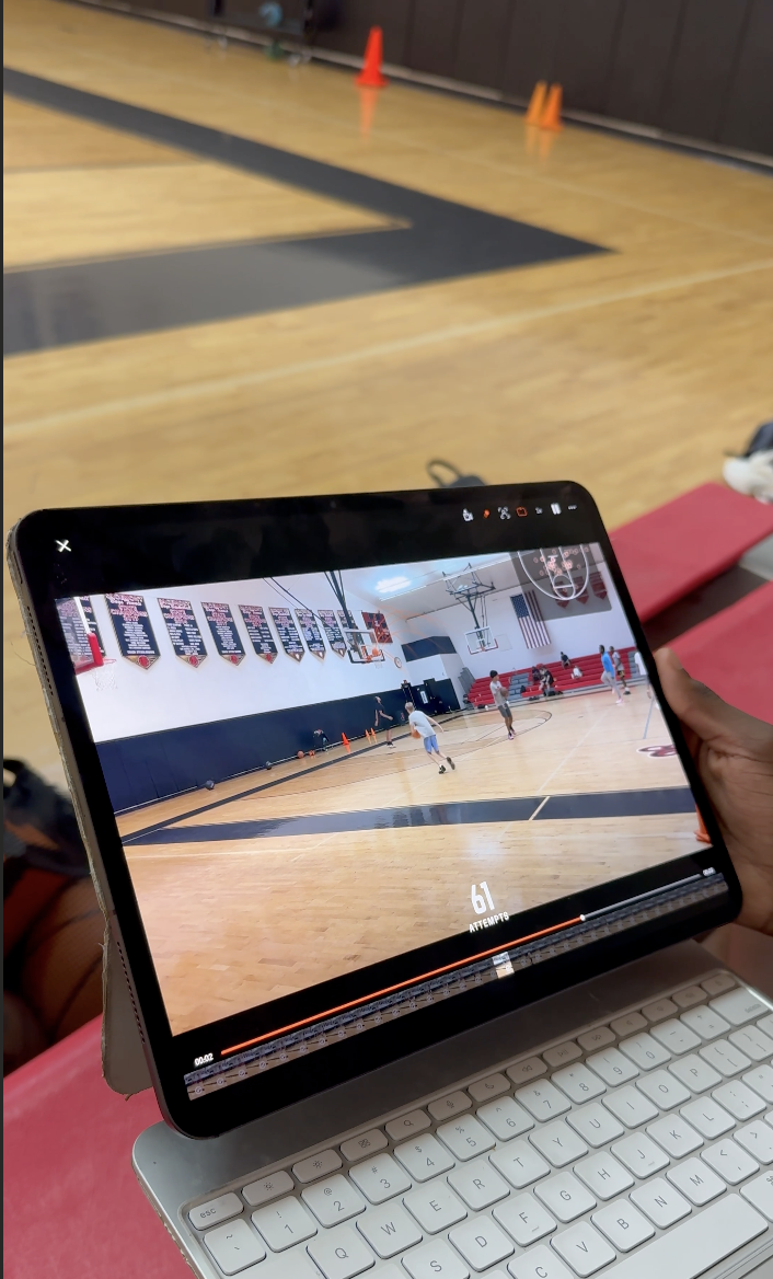 Un athlète et son mentor regardent un match sur une tablette au bord du terrain, pendant une séance vidéo