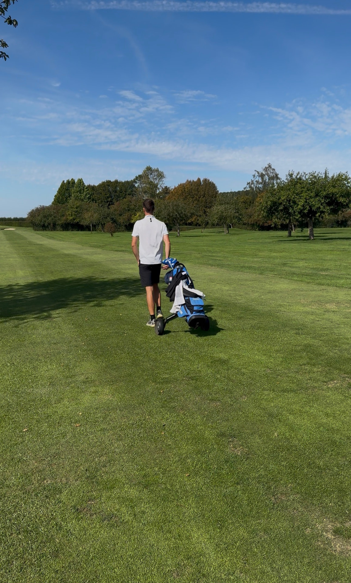 Un joueur de golf marche seul sur le fairway en tirant son chariot
