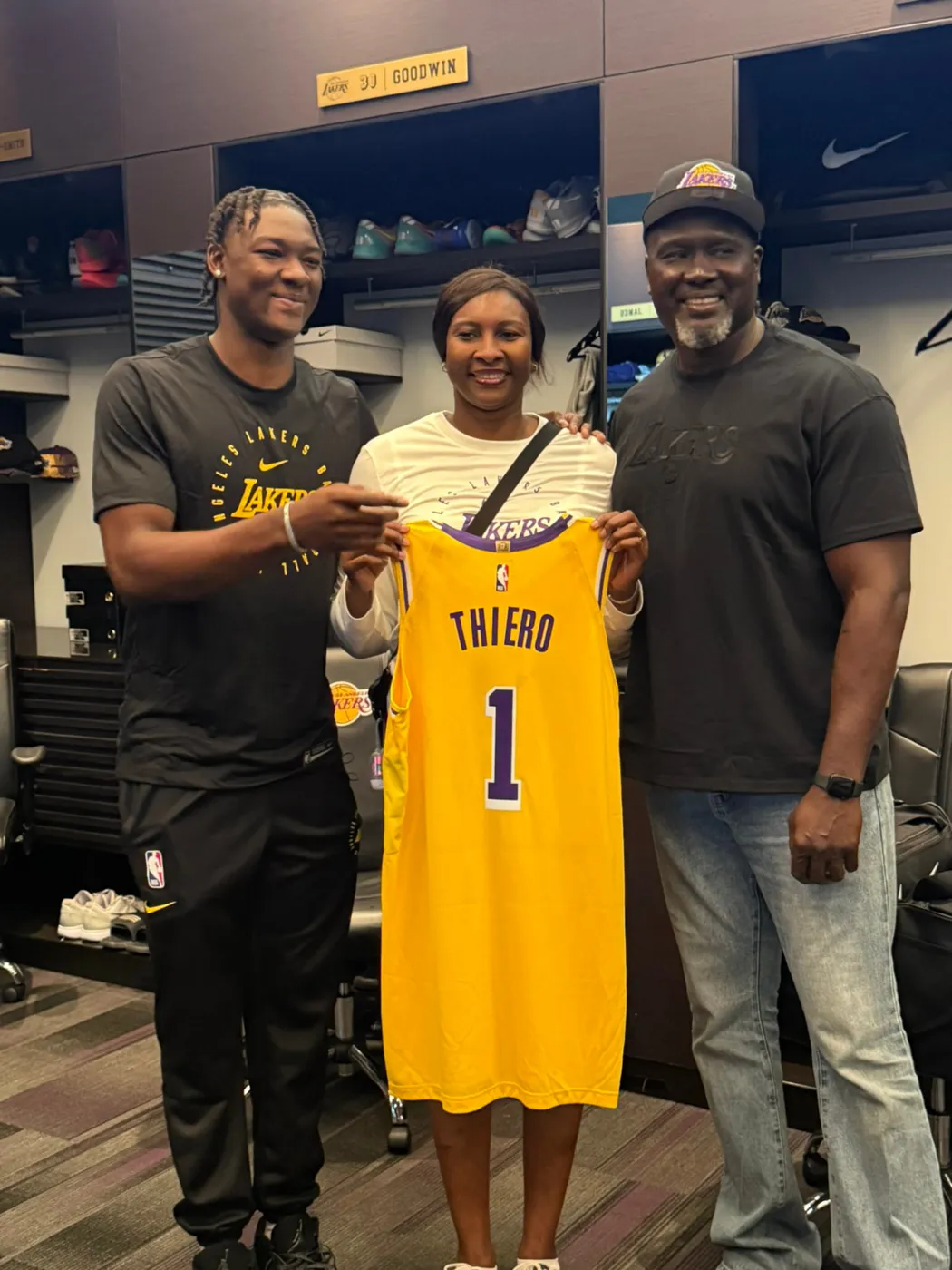 Un joueur professionnel et ses parents présentant son maillot floqué dans le vestiaire de sa nouvelle franchise